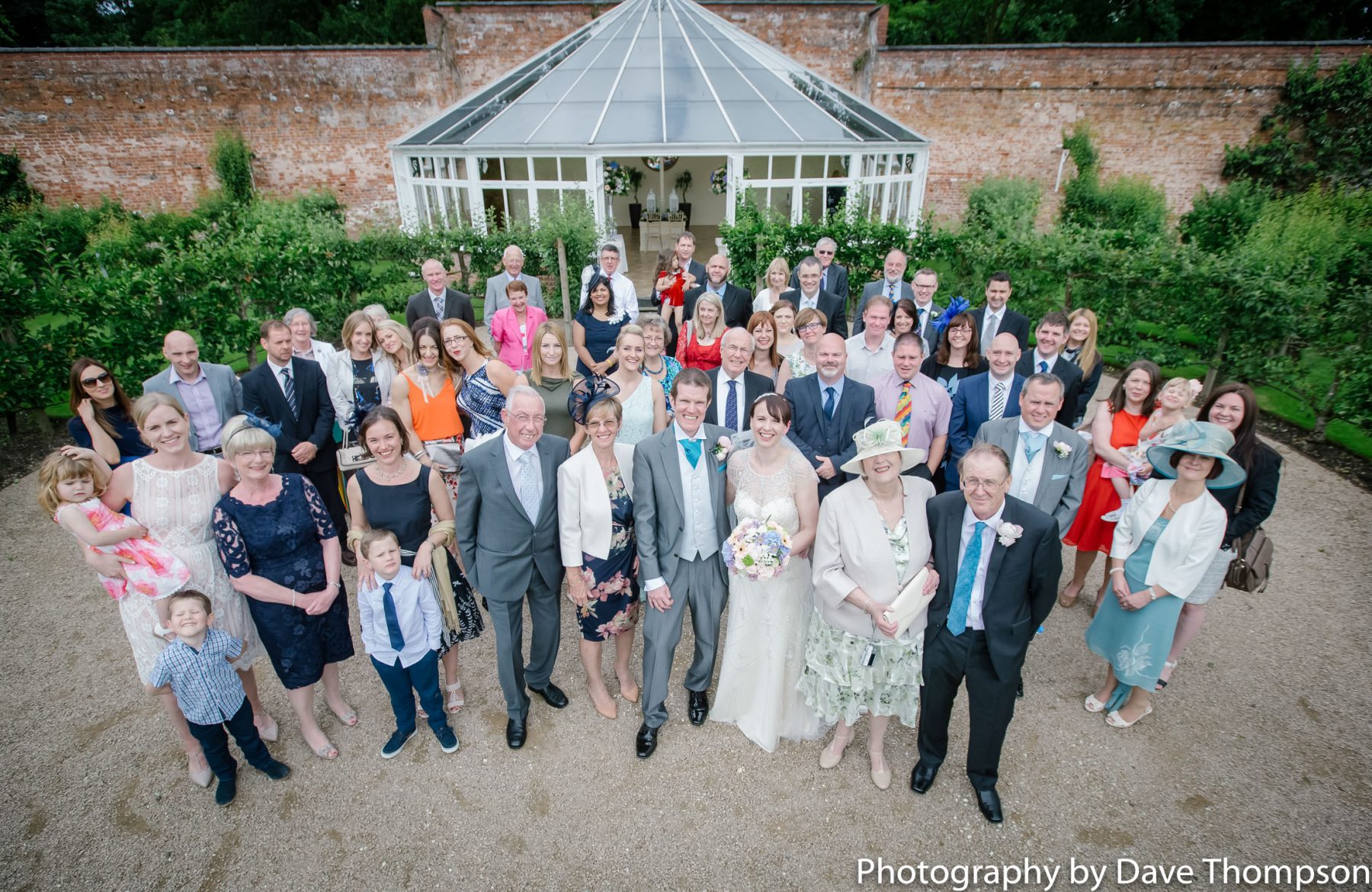 All the wedding guests gather for a photograph outside the glass house.