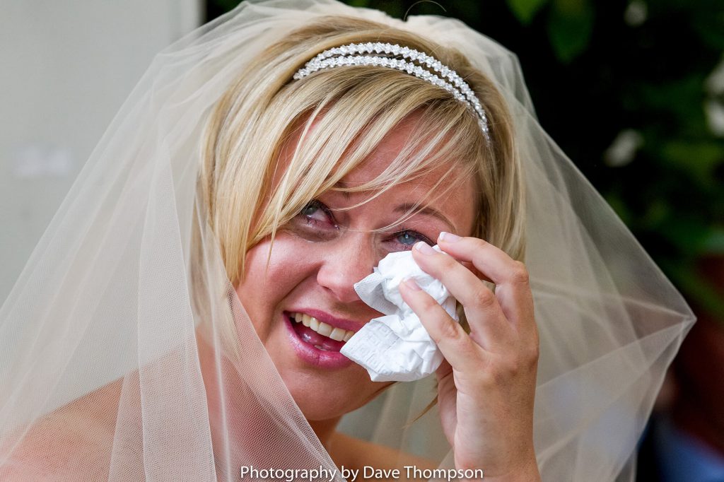 The bride wipes her eyes during her wedding