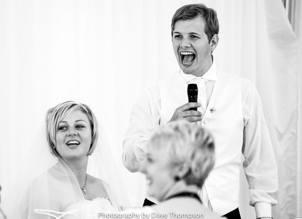 The groom laughs during his speech