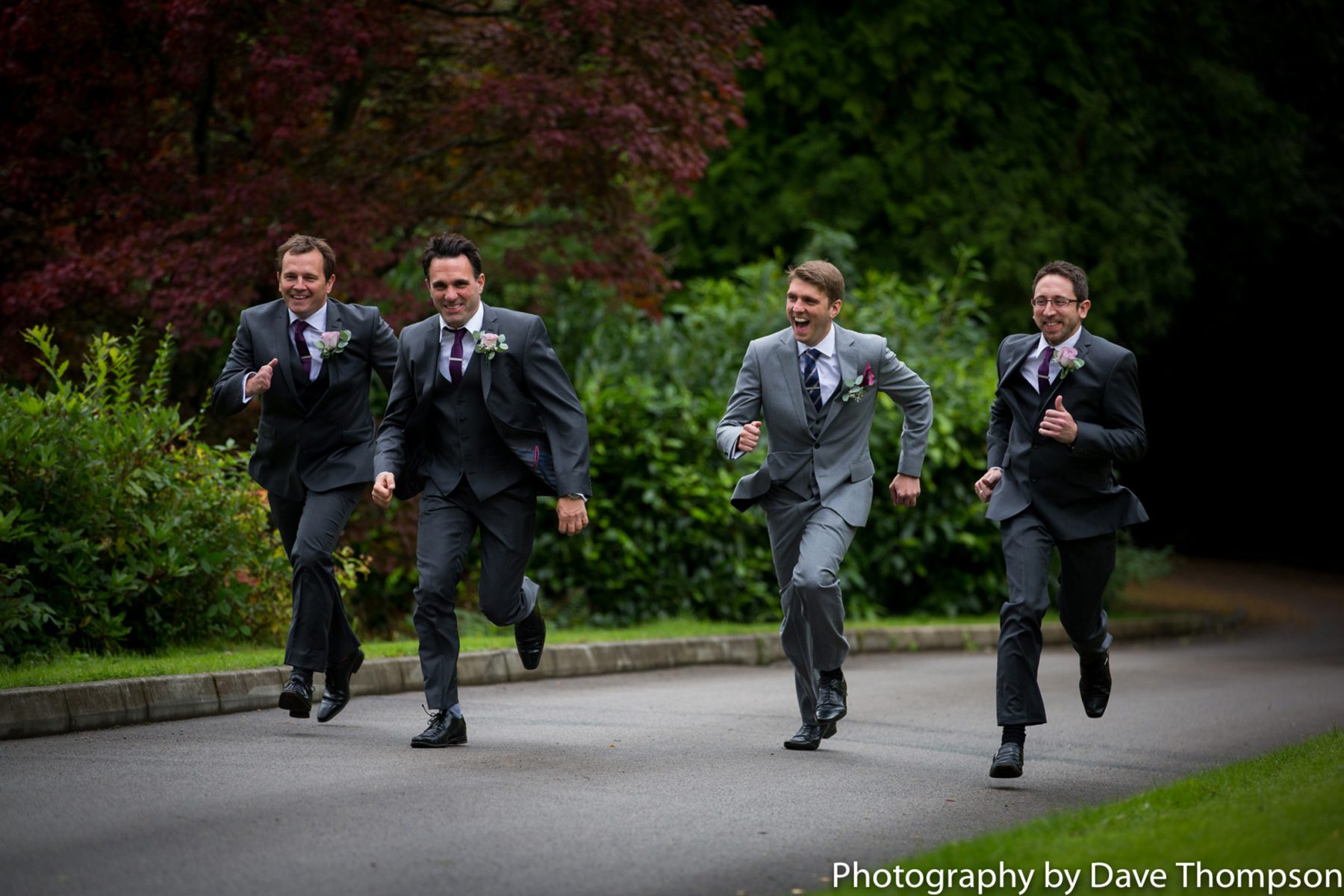 The best man chases the groomsmen up the winding driveway