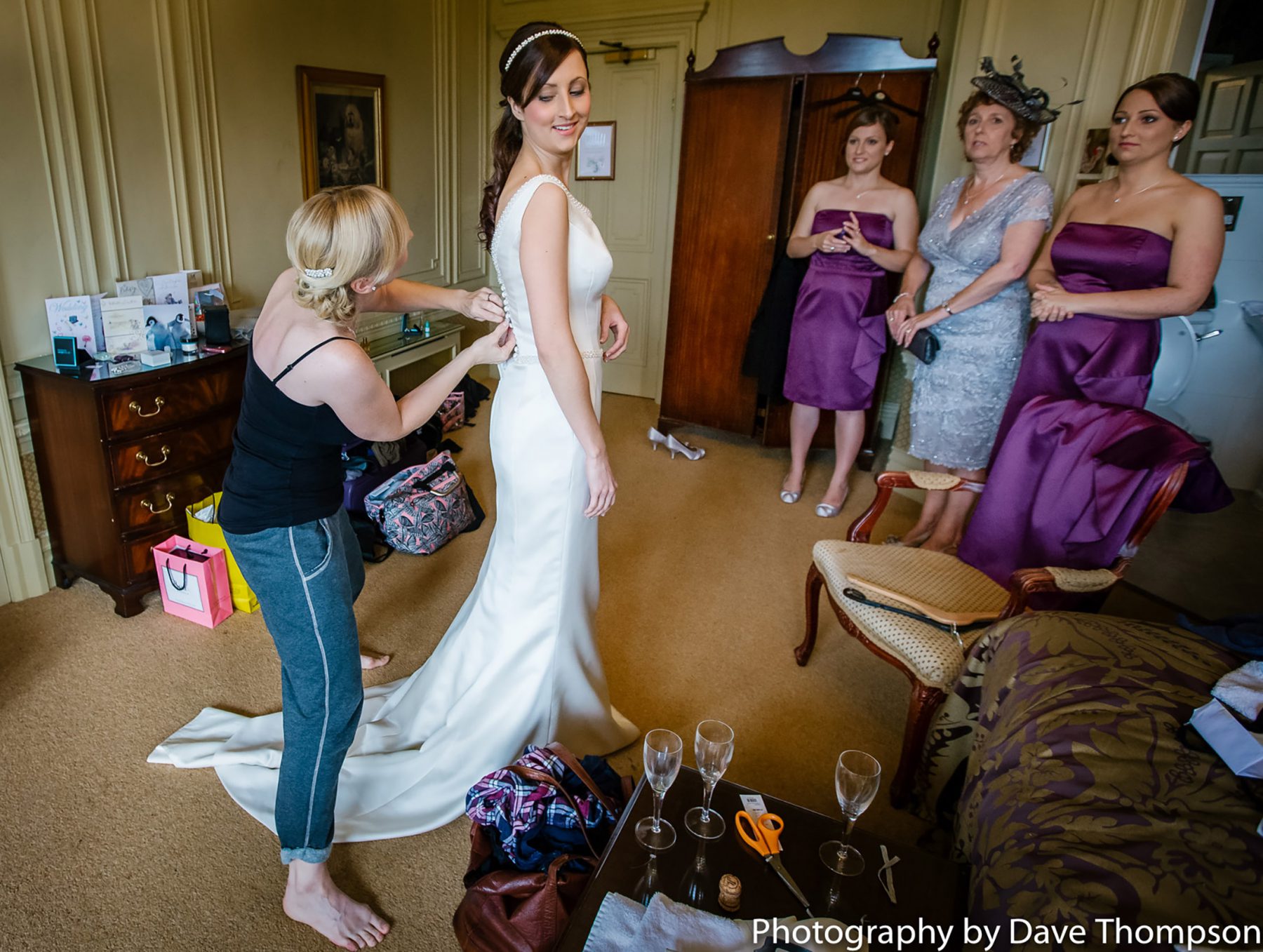 One of the bridesmaids helps the bride get into her dress