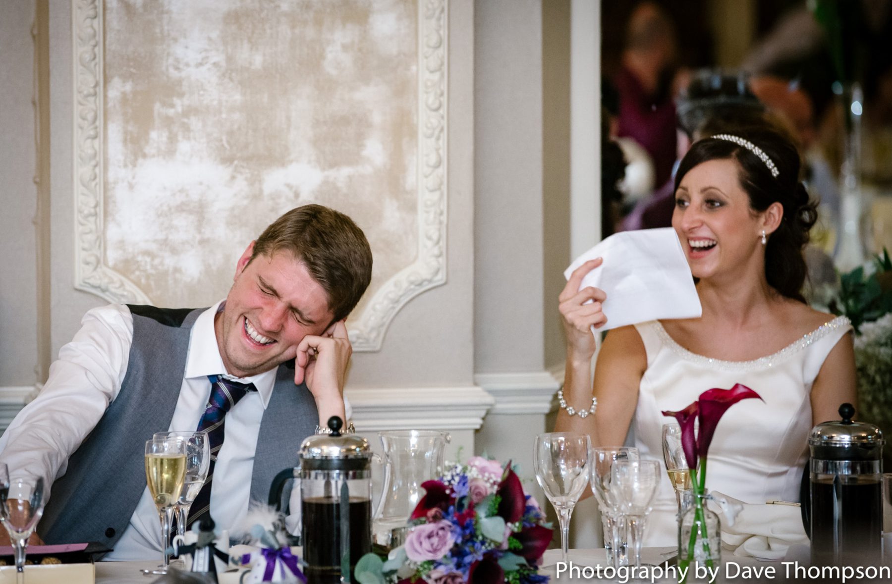 The bride and groom laugh during the best mans speech.