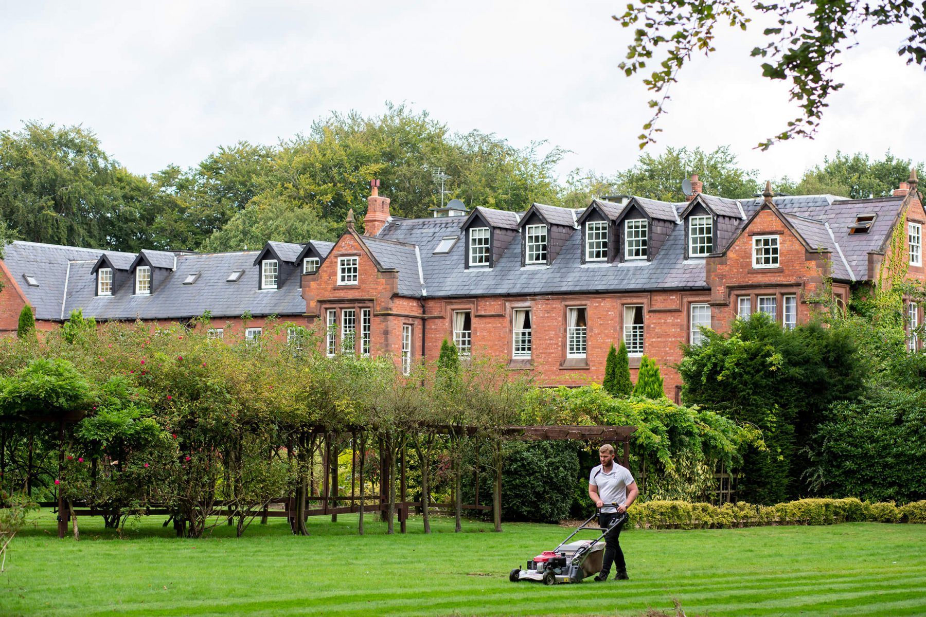 A member of staff mows the lawn outside Nunsmere Hall