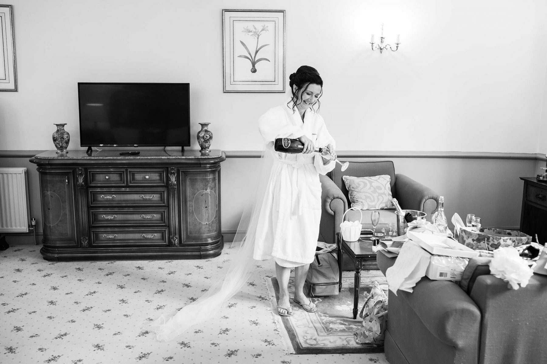 The bride urs herself a glass of champagne before her wedding
