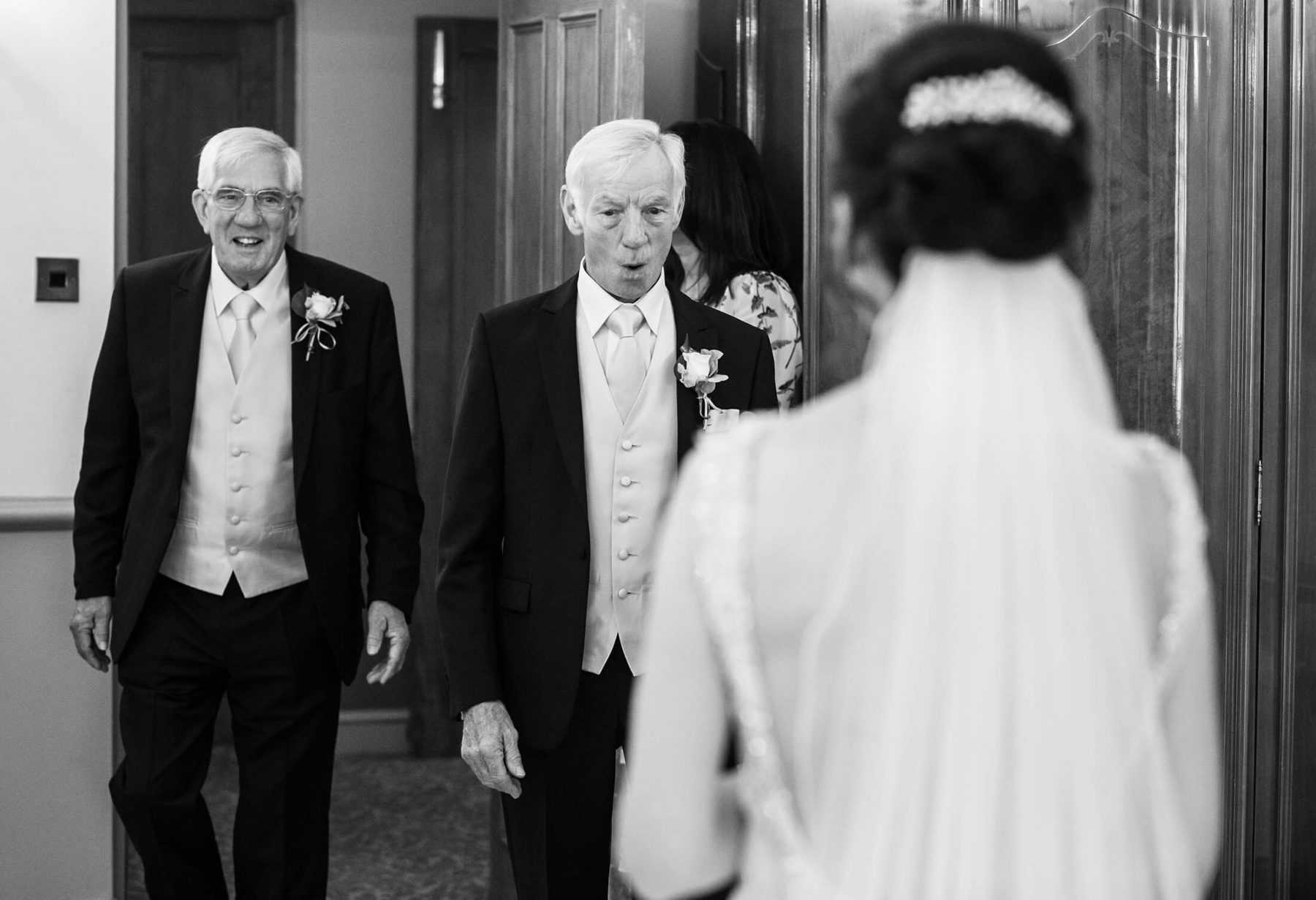 The bried's father and step father react as they see her in her dress