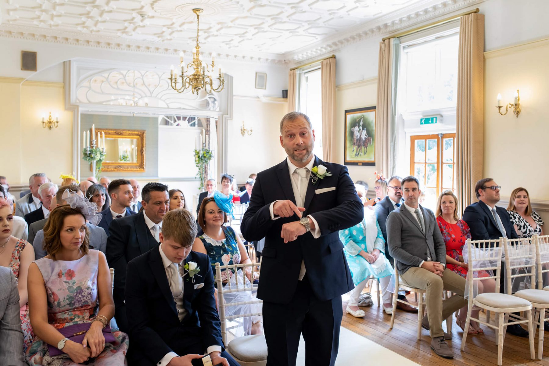 A groom points to his watch as the bride arrives late.