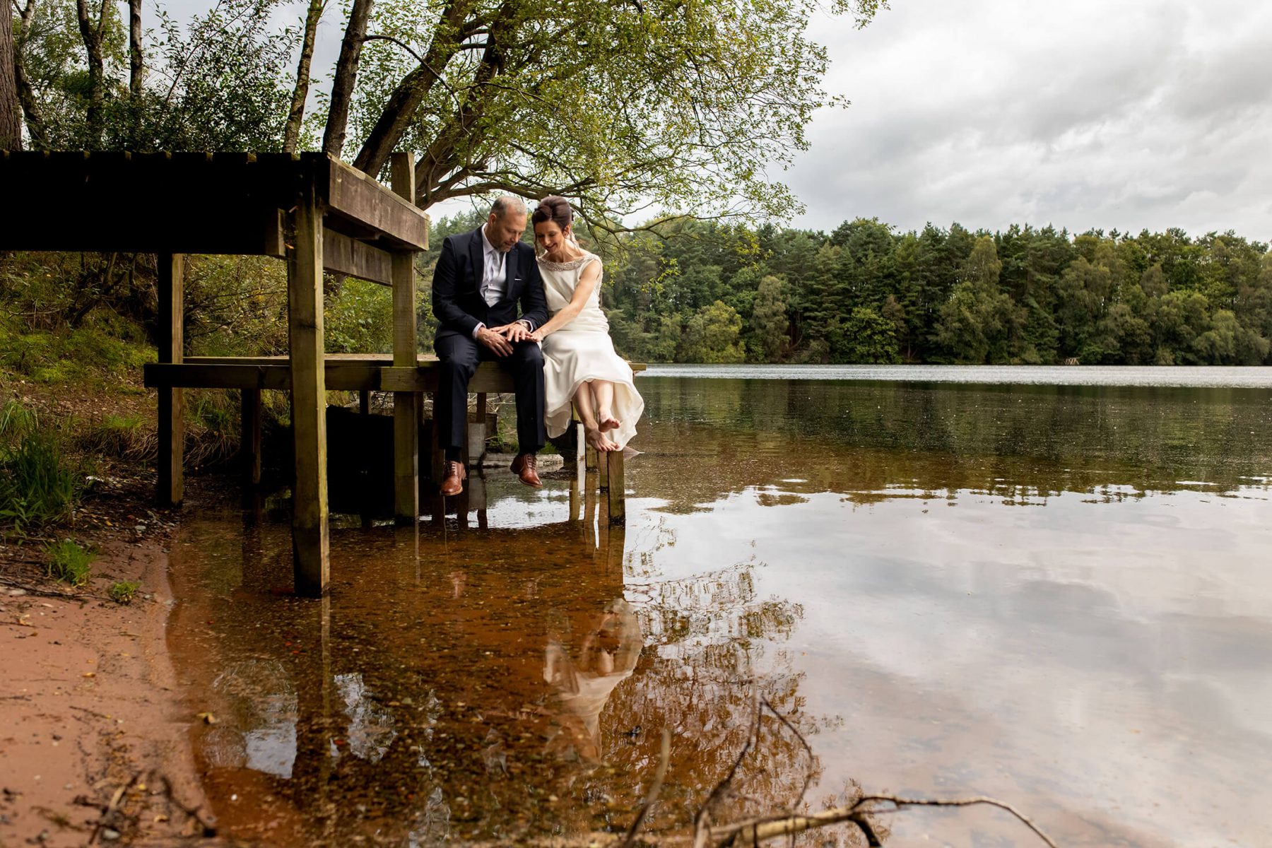 A bride and green sit by the 60acre lake at Nunsmere Hall
