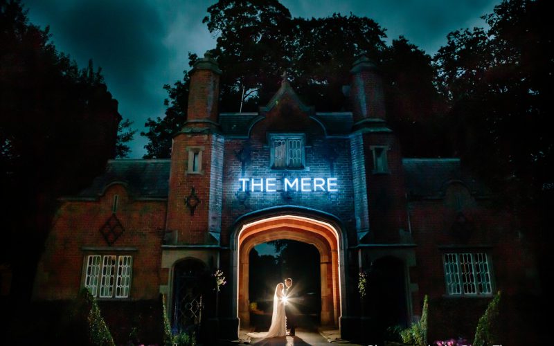 The Bride and Groom beneath the arch at the entrance to The Mere Resort