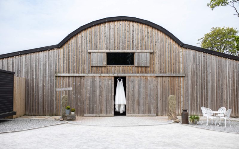 Alcumlow Wedding Barn with a dress hung in the doorway of the barn