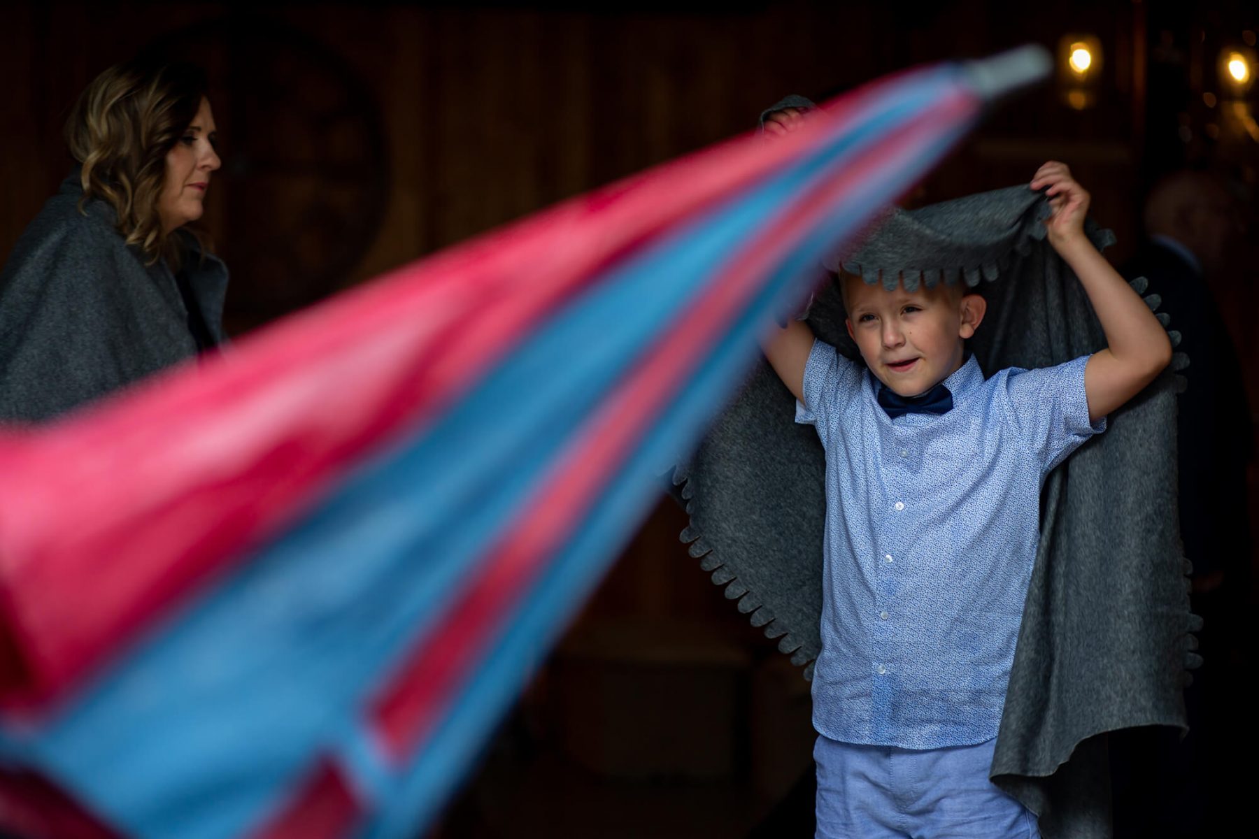 A young boy uses a blanket to keep warm in the rain.