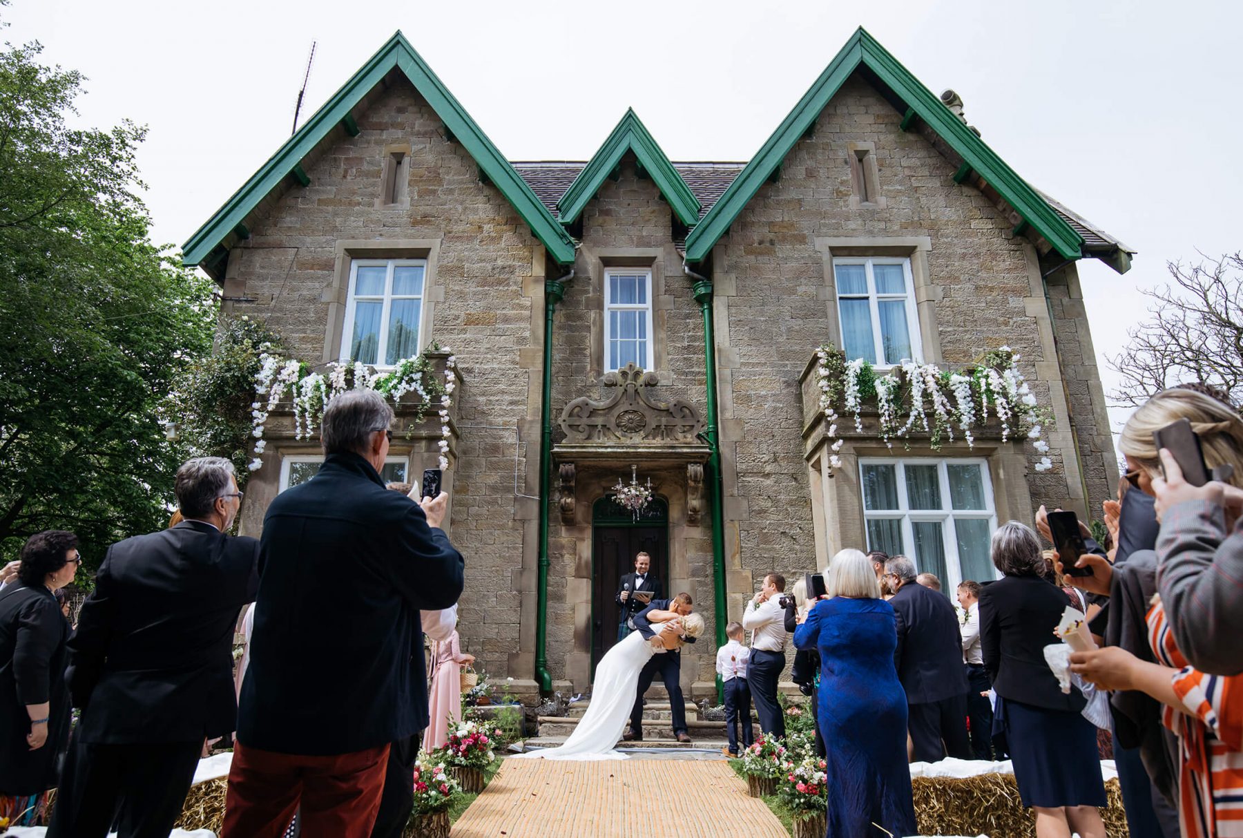 The bride and groom kiss outside a county house following their wedding