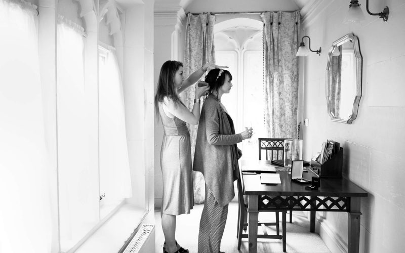 A bride has her hair prepared by a hairdresser before her wedding at Combermere Abbey