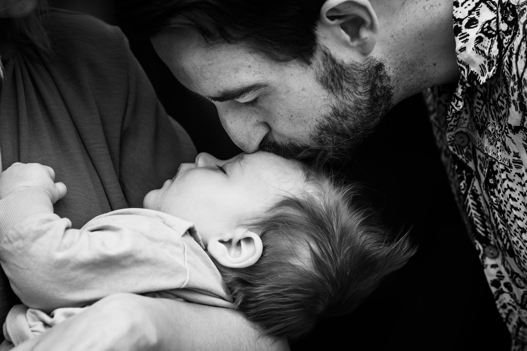 A father kisses his new born son's head