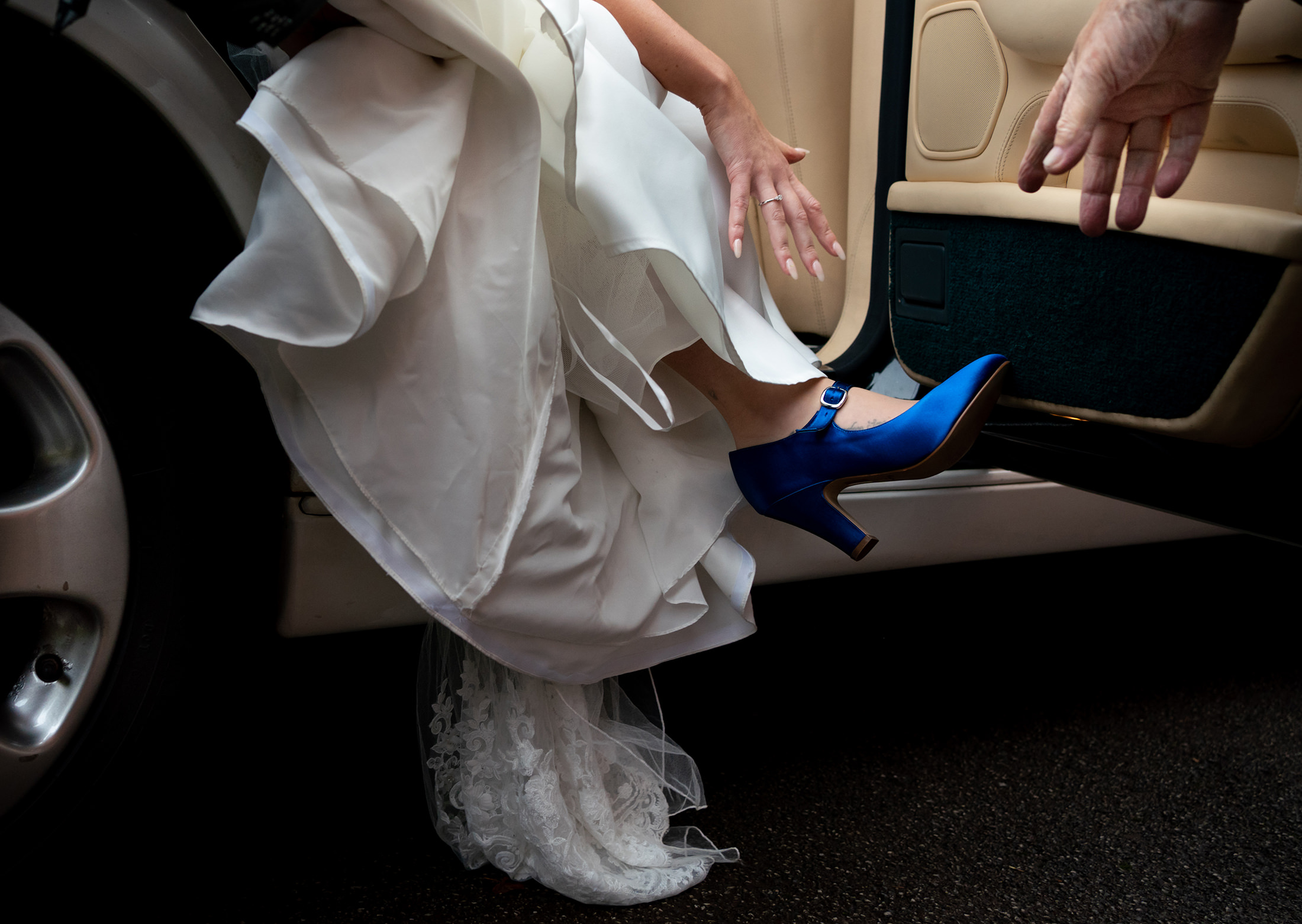 A bride steps out of the car wearing a blur shoe during this wedding in Altrincham in Cheshire