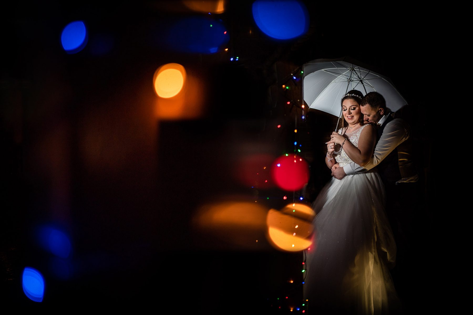 A creative off camera flash photograph of the bride and groom in the rain