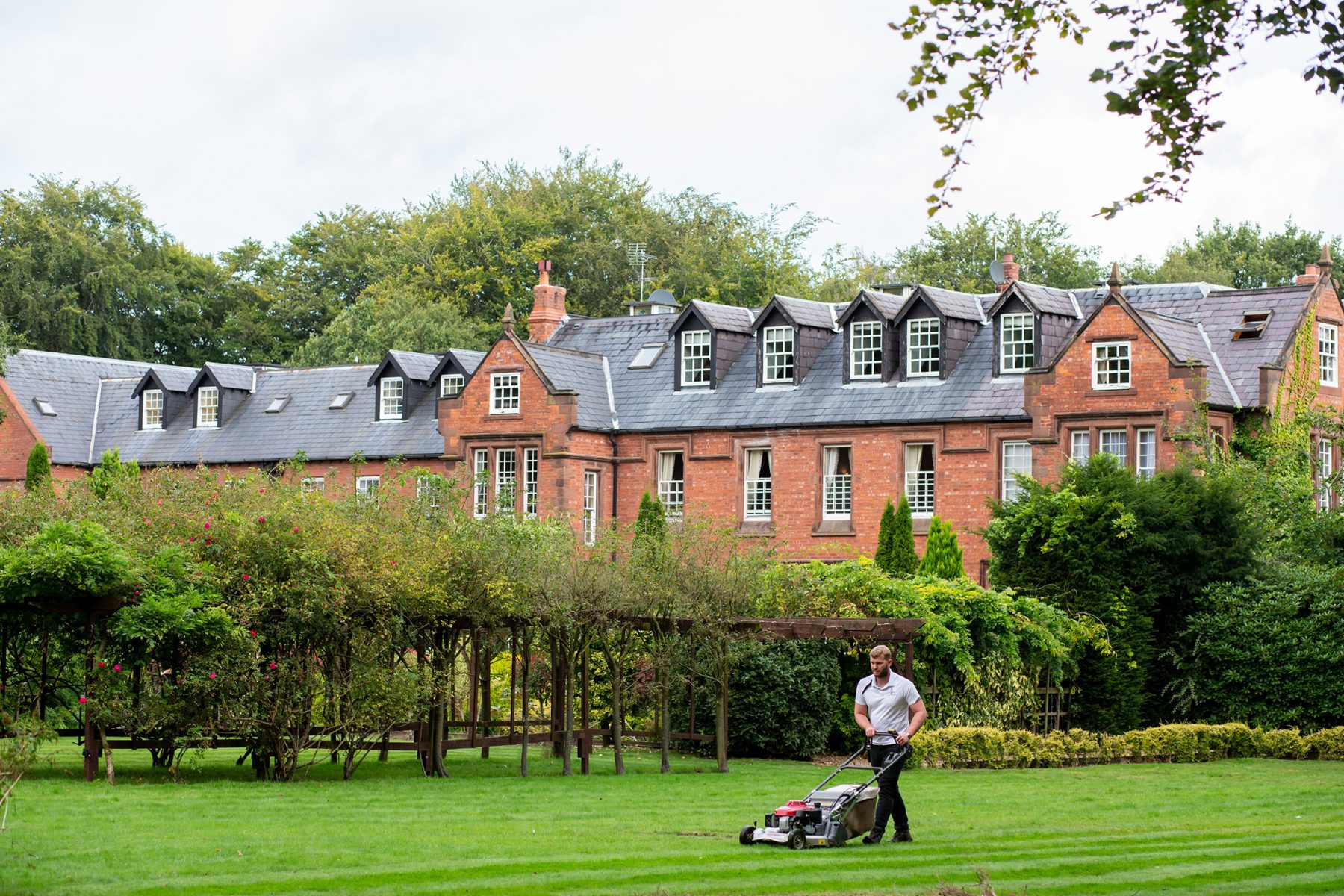 A member of the groundstaff mows the lawn at Nunsmere Hall in Cheshire